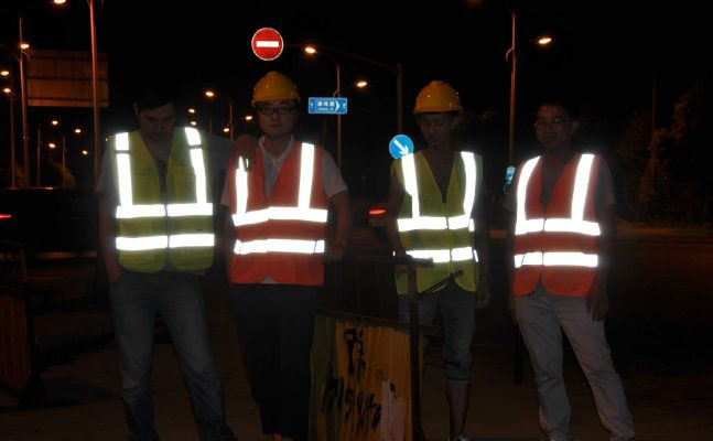 công nhân sửa chữa đường mặc áo bảo hộ phản quang trong đêm